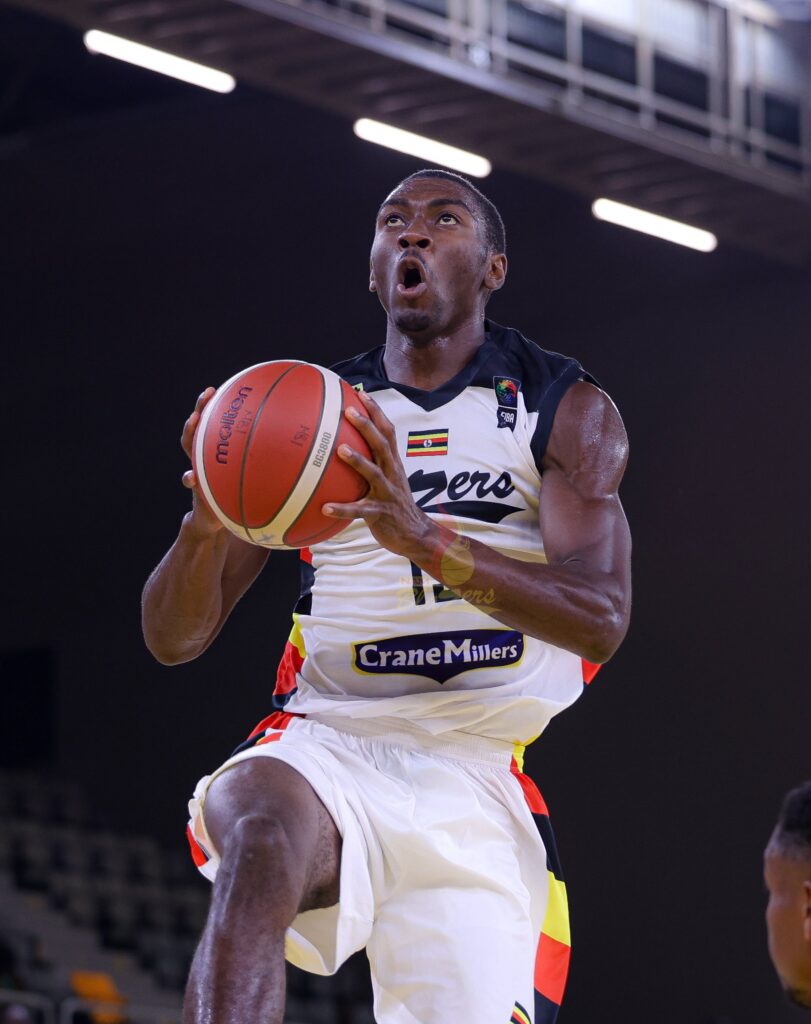 Fataki Nyembo holds the basketball while rising towards the basket in Namuwongo Blazers’ white kit.