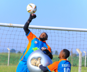 Kitara goalkeeper Joel Mutakubwa reaches for a ball during a training drill alongside fellow goalkeeper Kibirige.
