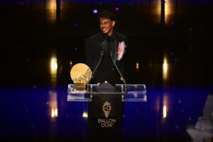 Lamine Yamal smiles at the podium beside his Young Talent trophy during the 2026 Ballon d’Or ceremony.