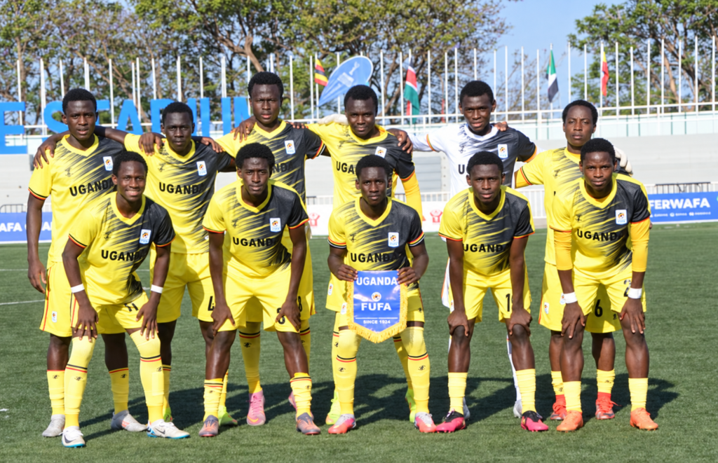 Uganda Cubs players pose for a team photograph in yellow and black kits, with the captain holding a FUFA pennant.